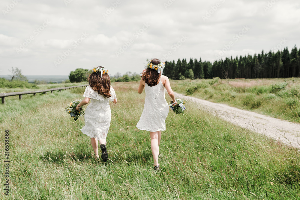 two girls running through a field with flowers two girls running through a field with flowers