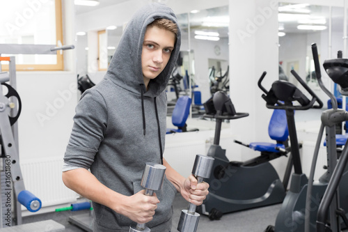 The teenager is engaged in bodybuilding in the gym.