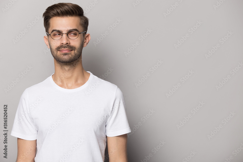 Suspicious young man wearing eyeglasses looking aside on copy space. Suspicious young man wearing eyeglasses looking aside on copy space.