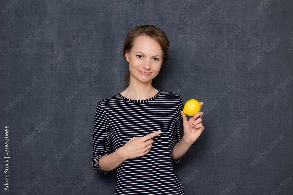 Portrait of happy positive girl pointing at lemon and smiling Portrait of happy positive girl pointing at lemon and smiling
