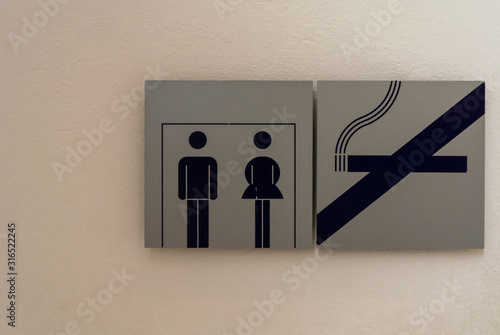 Toilet sign and no smoking sign on the white cement wall