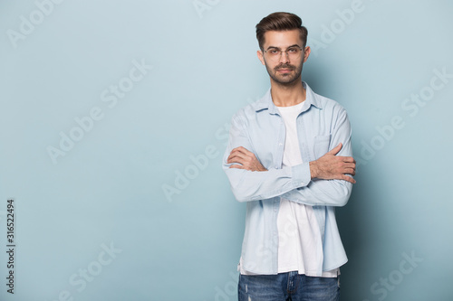 Confident young man standing near blank empty copy space.