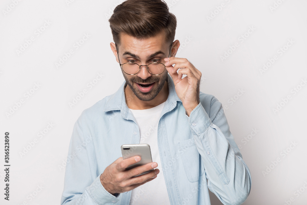 Young shocked man reading email with unbelievable news. Young shocked man reading email with unbelievable news.