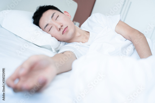 side view of bearded man sleeping on bed, lying on side