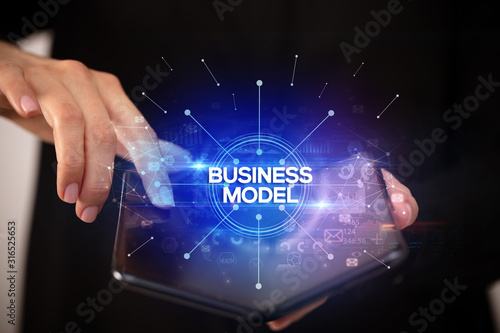Businessman holding a foldable smartphone with BUSINESS MODEL inscription, new business concept