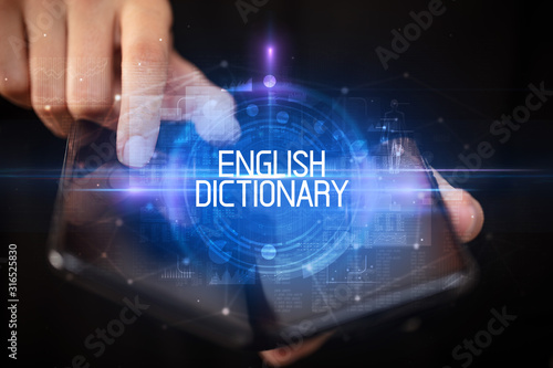 Young man holding a foldable smartphone with ENGLISH DICTIONARY inscription, educational concept