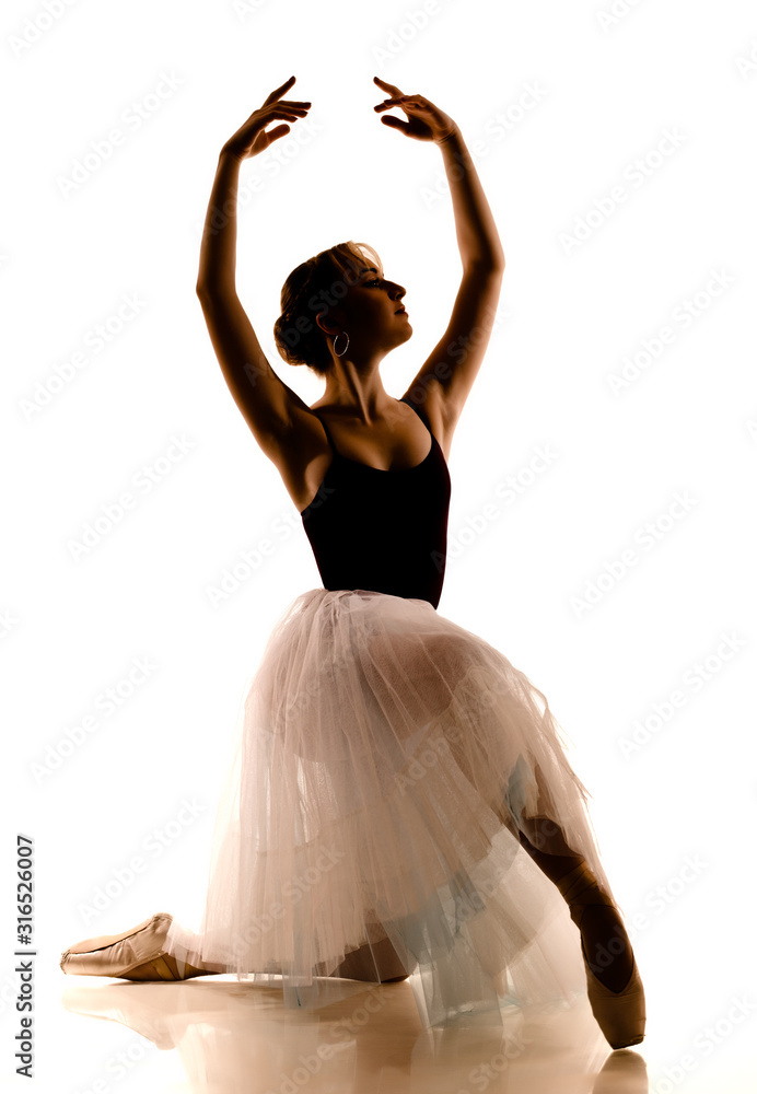 Fototapeta premium Silhouette of young beautiful ballerina in white tutu and pointe shoes doing dancing pose