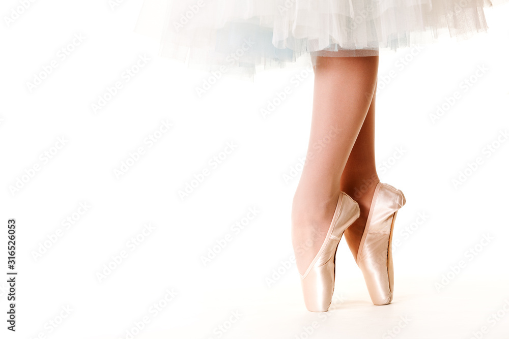 Legs of ballerina woman in white tutu and pointe shoes over white background Legs of ballerina woman in white tutu and pointe shoes over white background