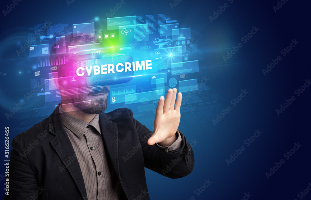 Businessman looking through Virtual Reality glasses with CYBERCRIME inscription, innovative security concept Businessman looking through Virtual Reality glasses with CYBERCRIME inscription, innovative security concept