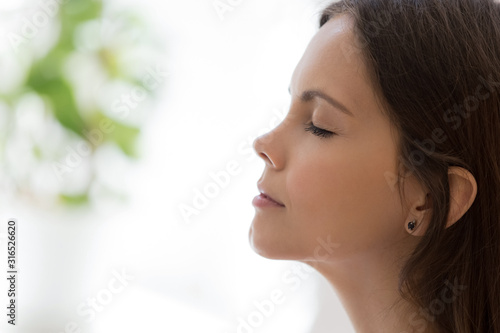 Closeup face attractive woman closed eyes daydreaming indoors