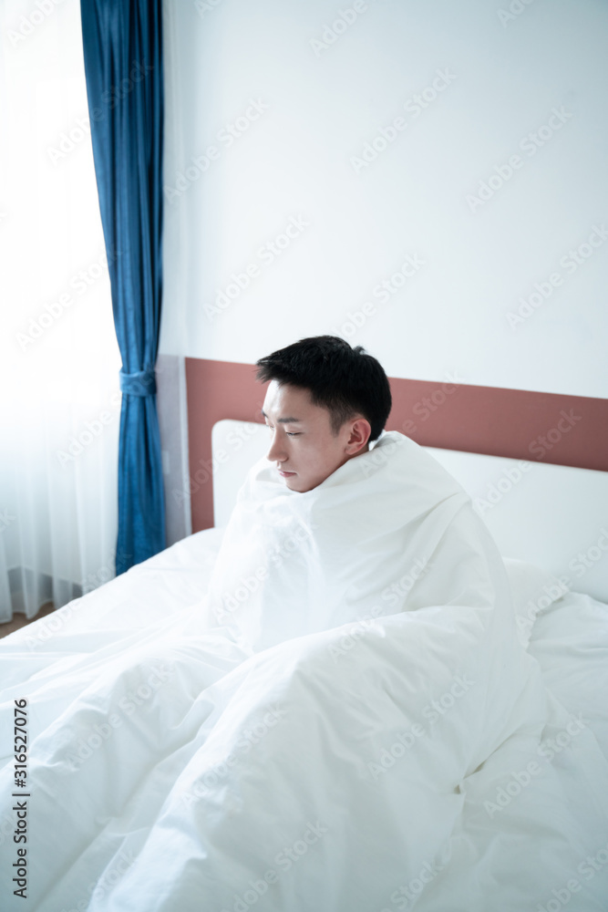 asian young man wrapped in plaid on bed