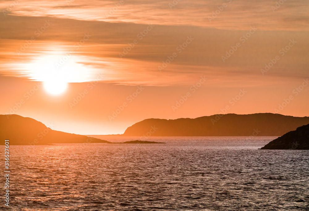 Beautiful Sunset with mountains and icebergs. Arctic circle and ocean. Sunrise horizon with pink sky during midnight sun.