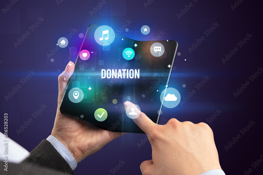 Businessman holding a foldable smartphone with DONATION inscription, social media concept Businessman holding a foldable smartphone with DONATION inscription, social media concept