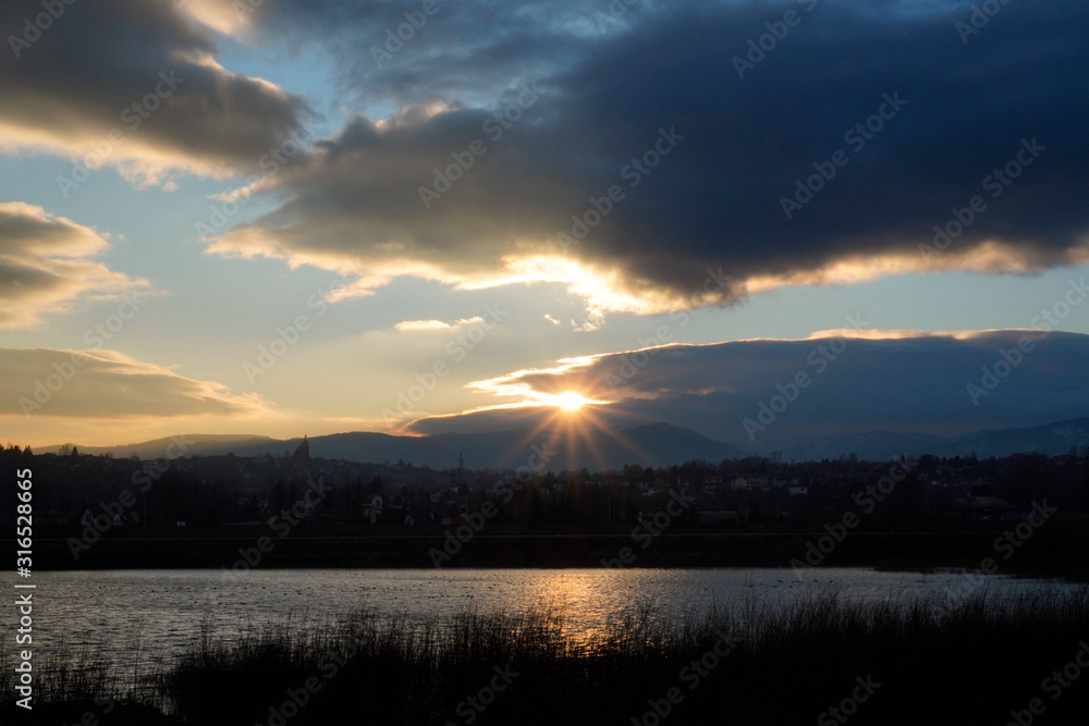 sunset over the mountains Beskids Slaski in Zywiec, Poland and clouds on the other side of the river or lake. bright clouds, illuminated by a magical contrast light, against the blue sky.