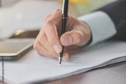 Businessman holding pen writing on paper document working,Close up hand write paperwork