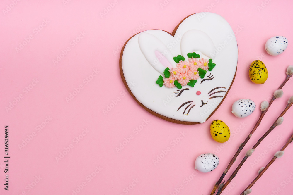 Easter bunny, gingerbread with glaze with quail eggs on pink background Copy space