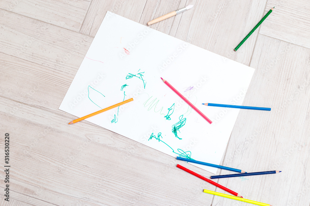 Sheet of paper and colour pencils on the floor. Baby art. Flat lay Sheet of paper and colour pencils on the floor. Baby art. Flat lay