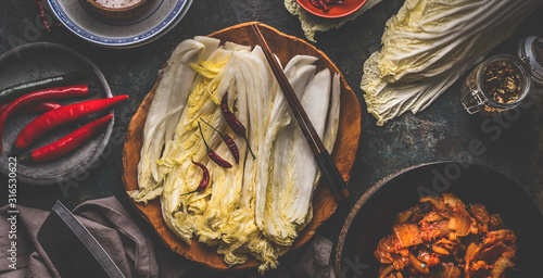 Fotografía Leaves of chinese cabbage in wooden bowl for kimchi making with ingredients and chopsticks