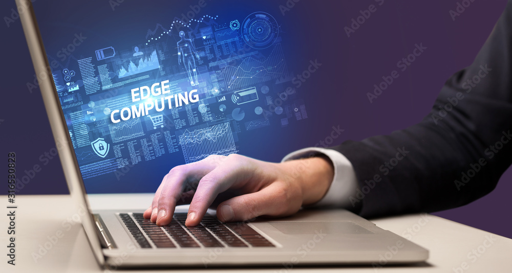 Businessman working on laptop with EDGE COMPUTING inscription, cyber technology concept Businessman working on laptop with EDGE COMPUTING inscription, cyber technology concept