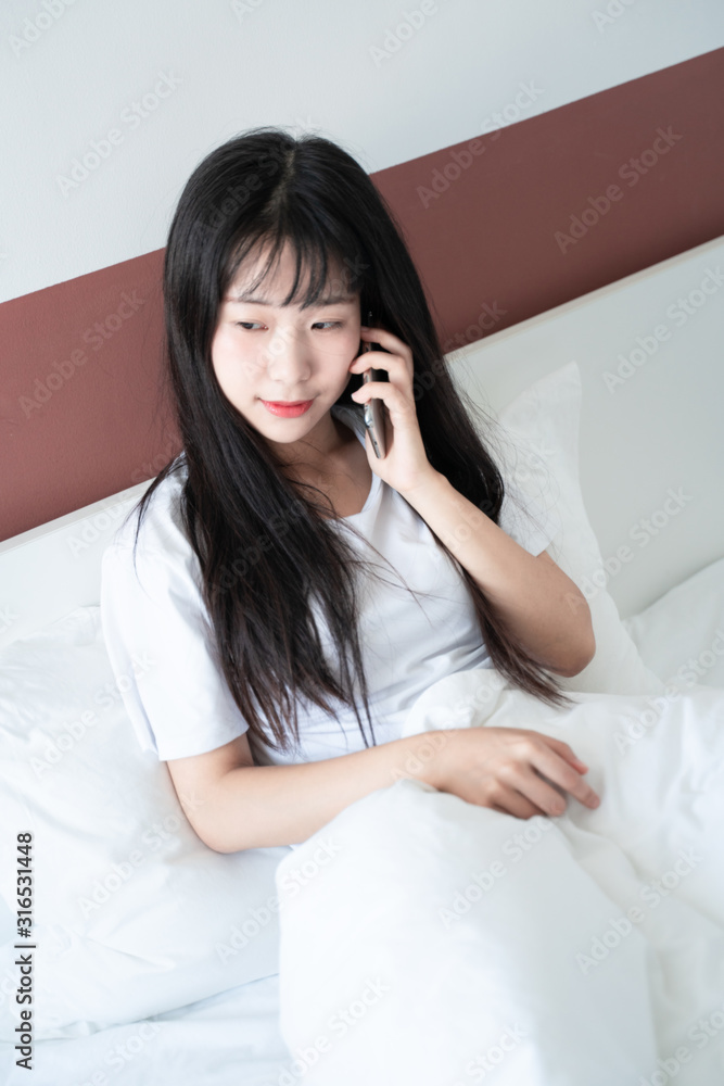 asian young woman making phone call on bed asian young woman making phone call on bed