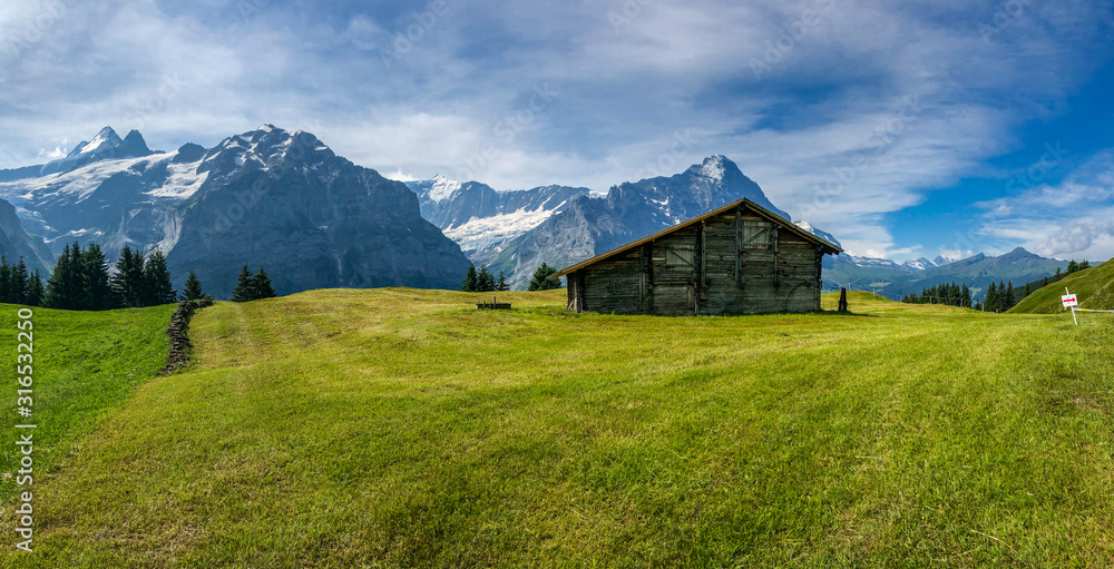 Scenic view of Swiss Alps in Grindelwald, single cottage house at the foot of the alpine, Switzerland