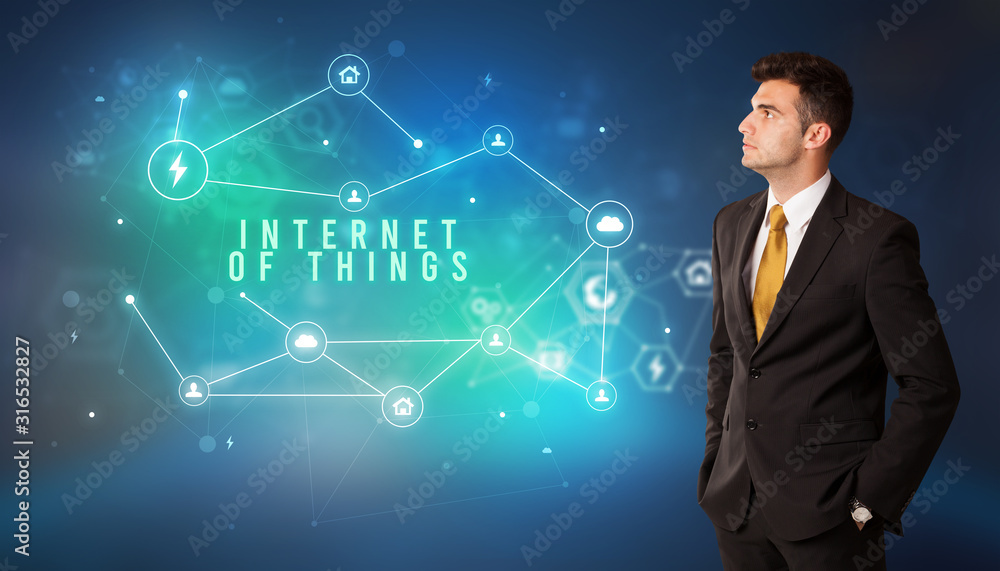 Businessman in front of cloud service icons with INTERNET OF THINGS inscription, modern technology concept Businessman in front of cloud service icons with INTERNET OF THINGS inscription, modern technology concept