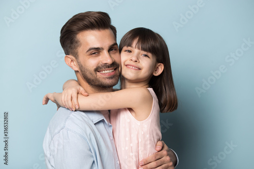 Little preschool girl embracing happy young father.