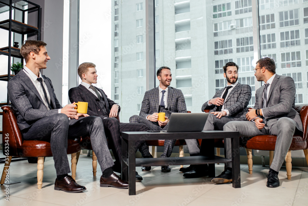free time at work of business team consisted of young men in suits, talking over a cup of tea together in office, successful partnership of happy male in modern office free time at work of business team consisted of young men in suits, talking over a cup of tea together in office, successful partnership of happy male in modern office