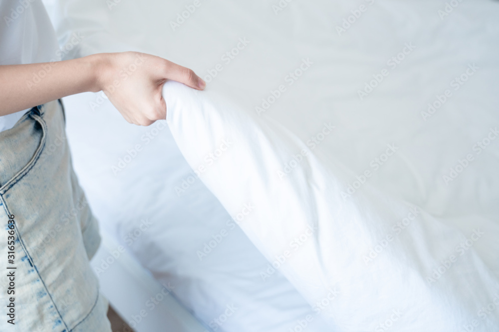 asian young woman making bed in bedroom asian young woman making bed in bedroom