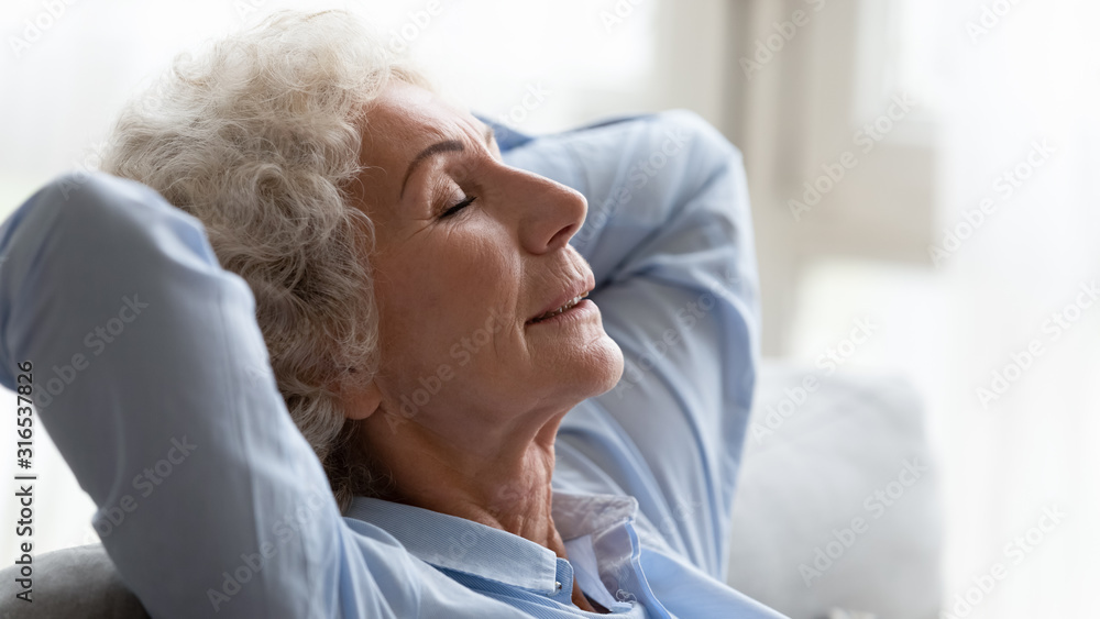 Close up peaceful older woman relaxing on cozy sofa Close up peaceful older woman relaxing on cozy sofa
