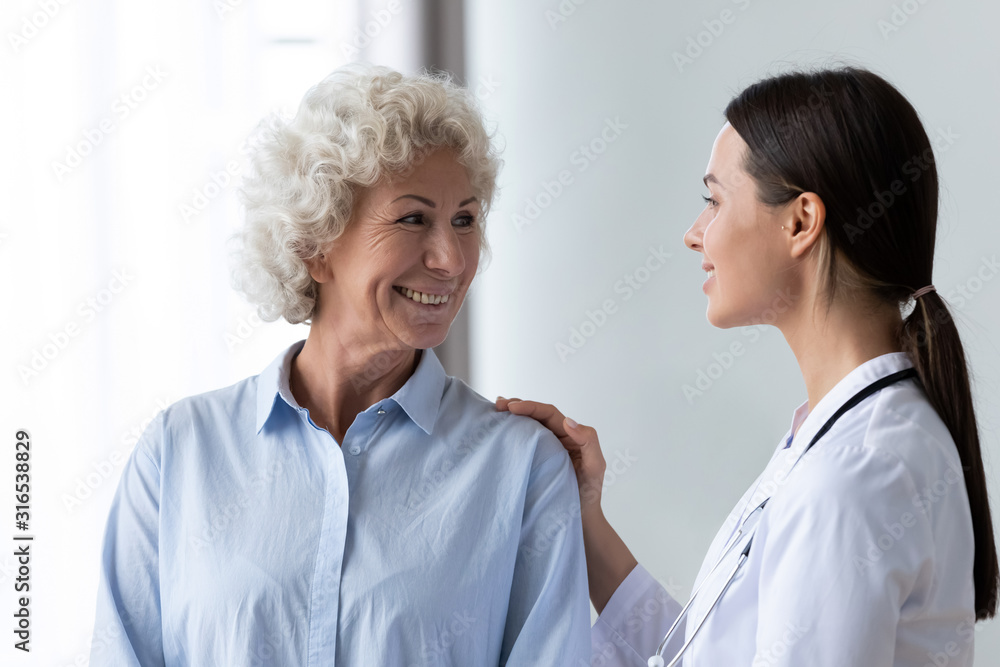 Caring nurse touching smiling older woman shoulder, expressing support Caring nurse touching smiling older woman shoulder, expressing support