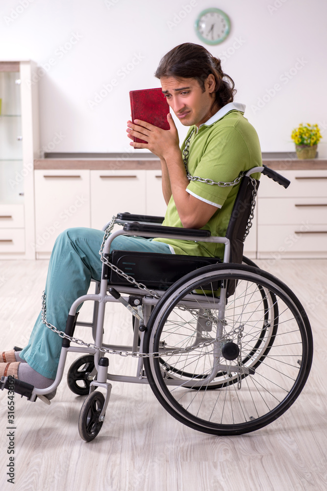 Young male invalid in wheel-chair suffering at home Young male invalid in wheel-chair suffering at home