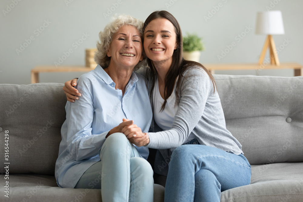 Portrait happy grandmother and granddaughter hugging, sitting on couch Portrait happy grandmother and granddaughter hugging, sitting on couch