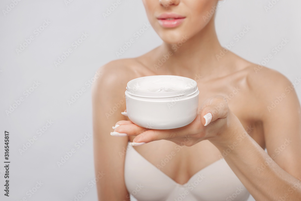 Skin care. Beauty Concept. Young woman holding cosmetic moisturizing cream. Soft skin and naked shoulders, model with light nude make-up, portrait of girl face with clean healthy skin. Dermatology Skin care. Beauty Concept. Young woman holding cosmetic moisturizing cream. Soft skin and naked shoulders, model with light nude make-up, portrait of girl face with clean healthy skin. Dermatology