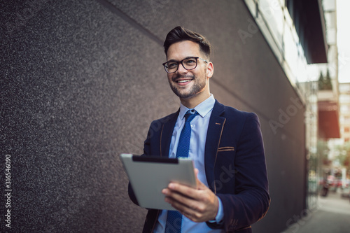 Portrait of businessman in glasses holding tablet