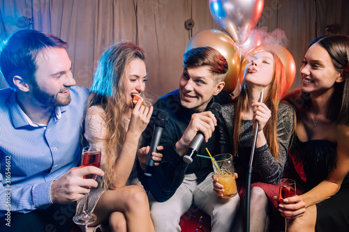 young caucasian students gathered to sing in karaoke bar, having fun together, karaoke and smoking hookah isolated in room