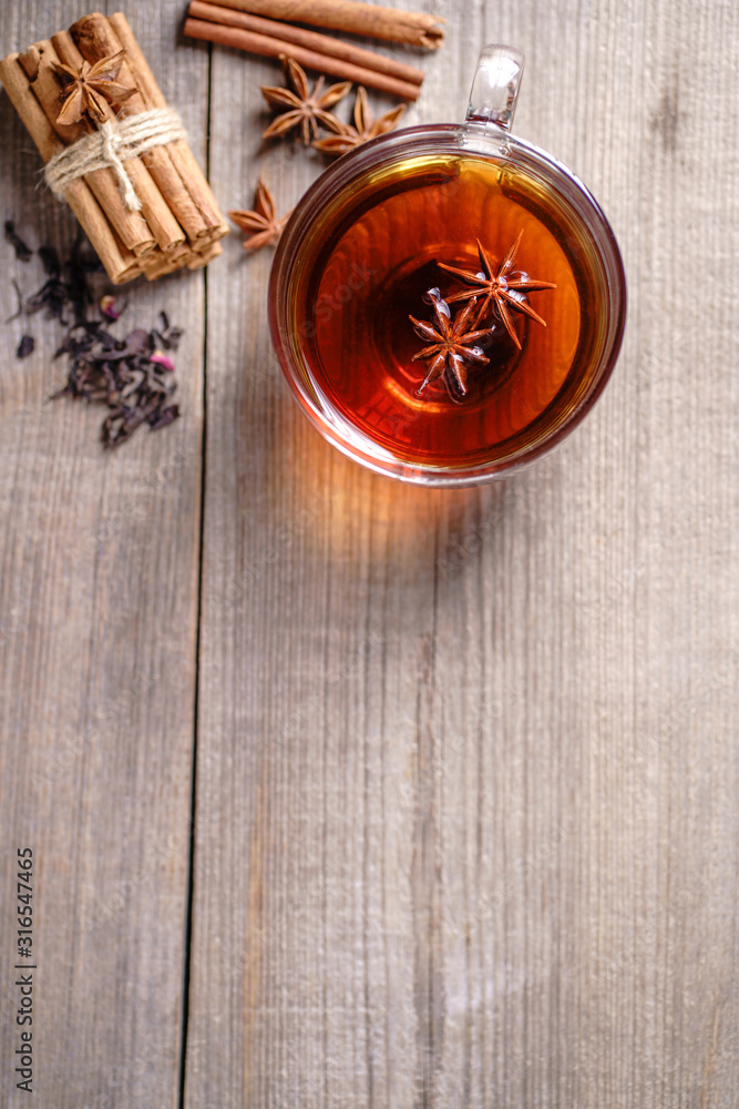 Spiced aromatic black tea. Hot warming beverage in a glass cup with anise and cinnamon on wooden background Spiced aromatic black tea. Hot warming beverage in a glass cup with anise and cinnamon on wooden background