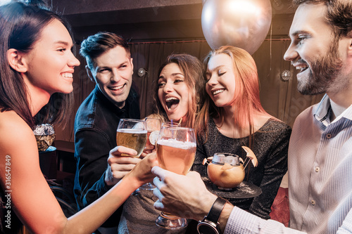 cheerful group of people smile and drink and have fun togeher in karaoke bar, beautiful girls and handsome guys chilling out and rocking together, enjoy