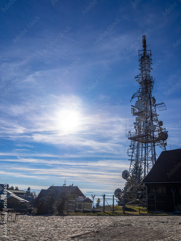 Radio Mast on Mountain top Jaworzyna Krynicka at blue sky and sun background, Poland.