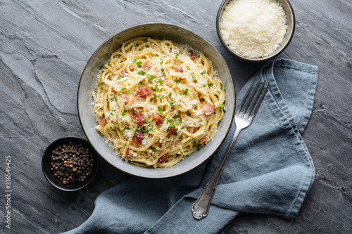 Classic pasta Carbonara, hearty Italian dish made with Spaghetti, egg, fried bacon, topped with grated Parmesan cheese and black pepper