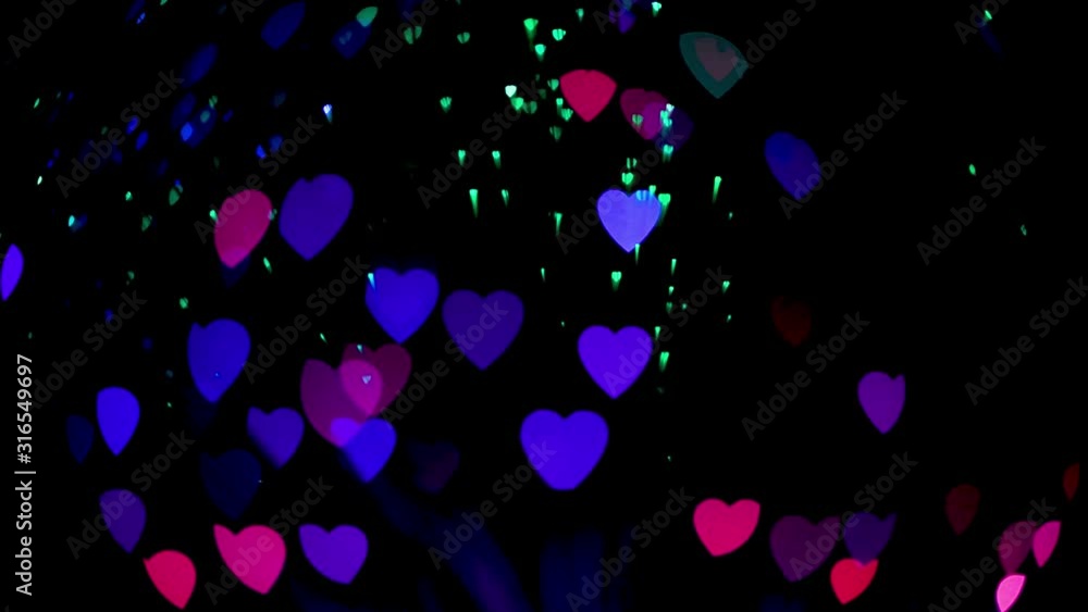Heart shaped creative bokeh blinking on black background. Selective focus. Abstract colorful background. 4K UHD video 3840x2160