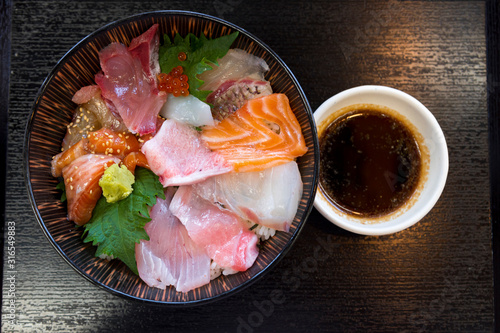 Premium fresh raw seafood mixed rice bowl (Kaisen-don/ Japanese tasty food), Japanese Rice with sashimi of tuna, Maguro, Otoro, salmon, squid and ikura (Salmon eggs) on wood background
