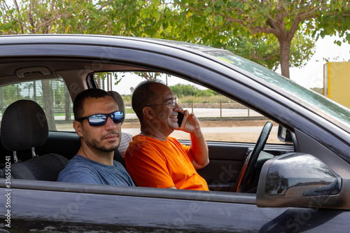 Man is driving his car, looking happy and smiling while is having conversation on his phone photo