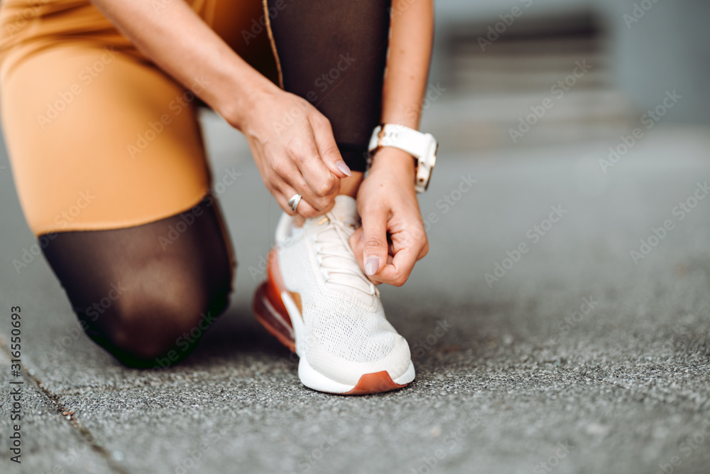 Close-up of active jogging female runner, preparing shoes for training and working out at fitness workout
