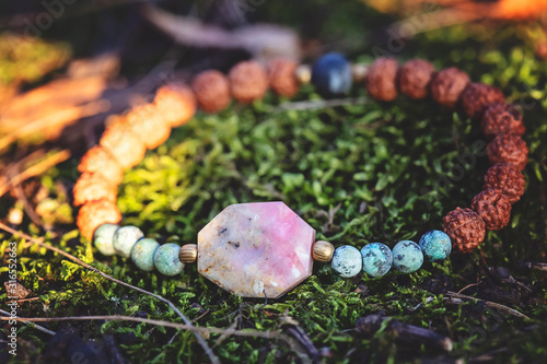 Beautiful female bracelet with fazeted opal stone and rudraksha seed on natural forest background photo