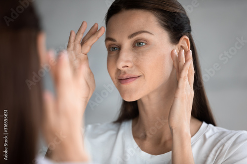 Close up beautiful woman with perfect skin looking in mirror