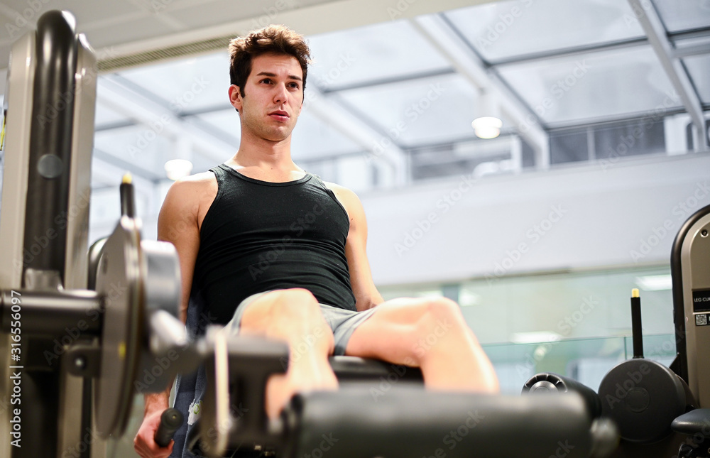 Gym seated leg curl machine exercise man in the gym