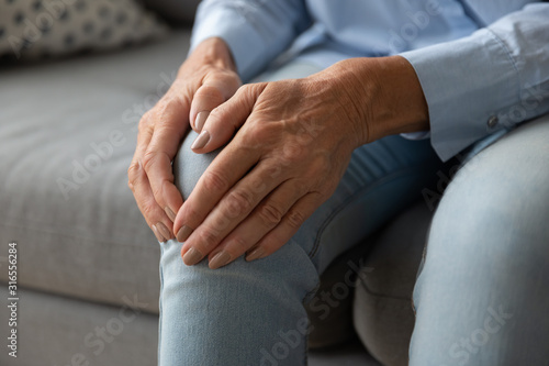 Close up older woman touching knee with hands  feeling pain