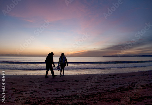 dog walkers on the beach at dawn