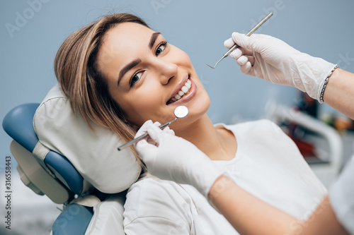 portrait of young smiling blond good-looking woman on dental examination, treating teeth in professional orthodontic clinic photo